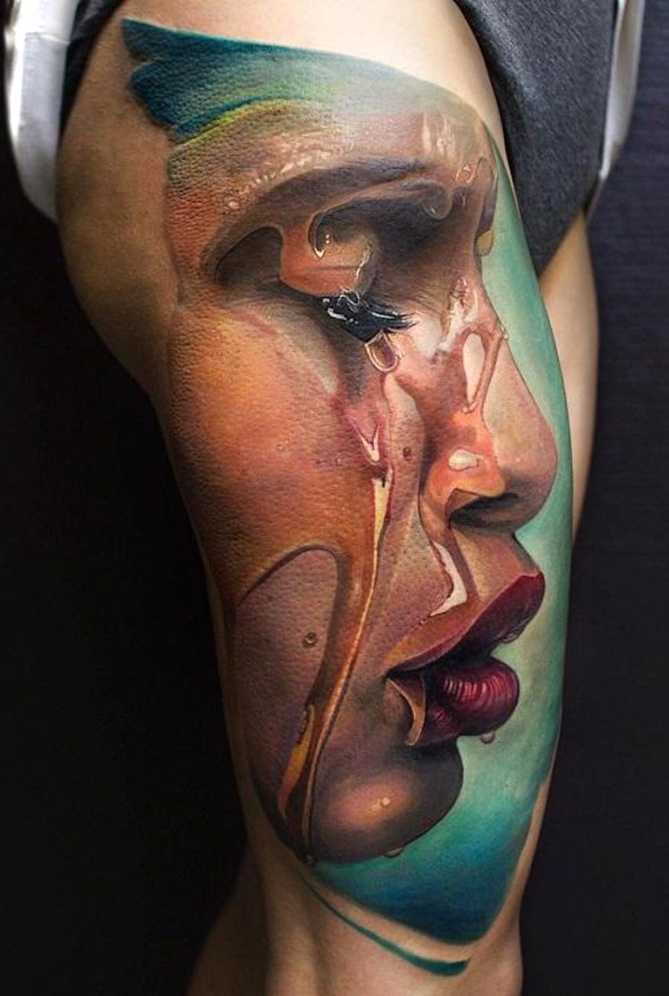 Realistic colored face tattooed on thigh