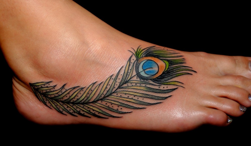 peacock feather tattoo on leg on black background